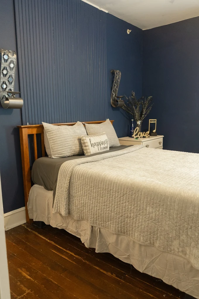 bed with white bedspread against blue wall.