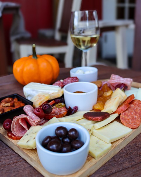 charcuterie board with cheese, olives, cured meats and wine.
