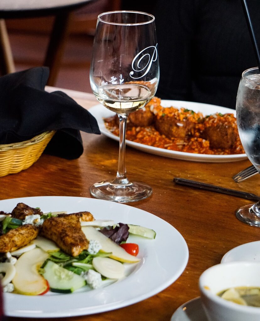 wine glass on table with food in plates on the table